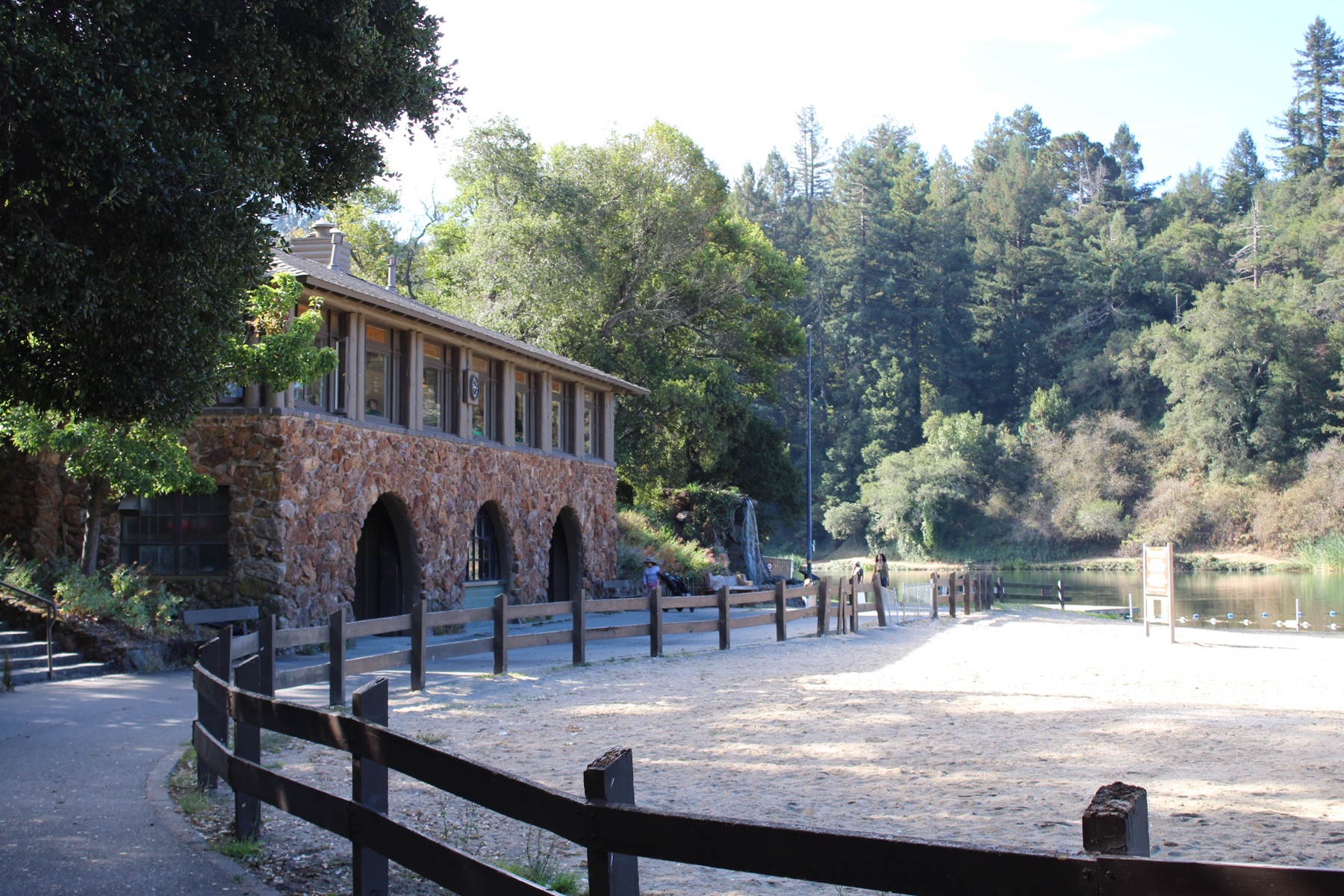 A stone boathouse beside a quiet lake, surrounded by wooded hills